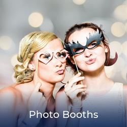 Guests dressed up for a photo in a booth at a wedding. Link to Photo Booths available for hire